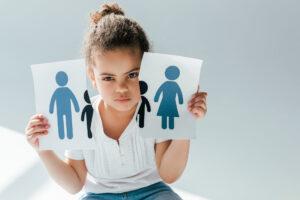 Kleines Kind, das zerrissenes Papier, mit Familie darauf, traurig in der Hand hält.