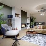 Design-Wohnzimmer im Dachgeschoss mit extravaganten Wohnaccessoires, wie Designer-Kamin und großem Sofa mit Sessel, viel Grün und Blumentöpfen.