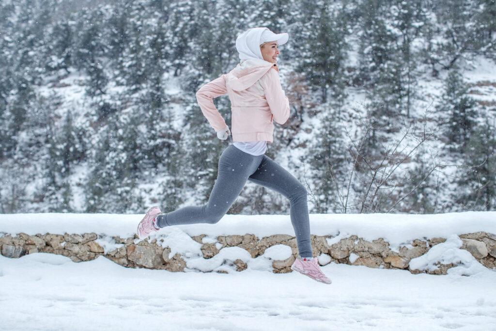 Frau treibt Sport und läuft im Winter in Thermoleggins durch den Wald
