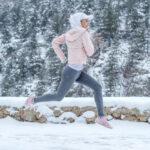 Frau treibt Sport und läuft im Winter in Thermoleggins durch den Wald