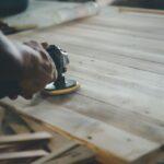 Handwerkliches Schleifen einer Holzoberfläche – Detailarbeit für ein nachhaltiges und ästhetisches Holzlager im Garten.
